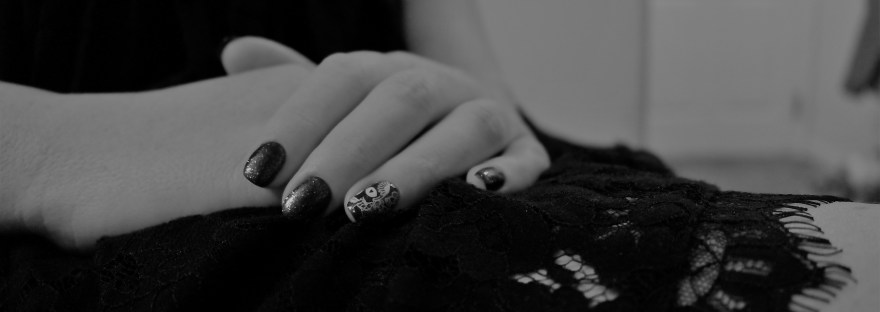 painted nails resting on black lace dress